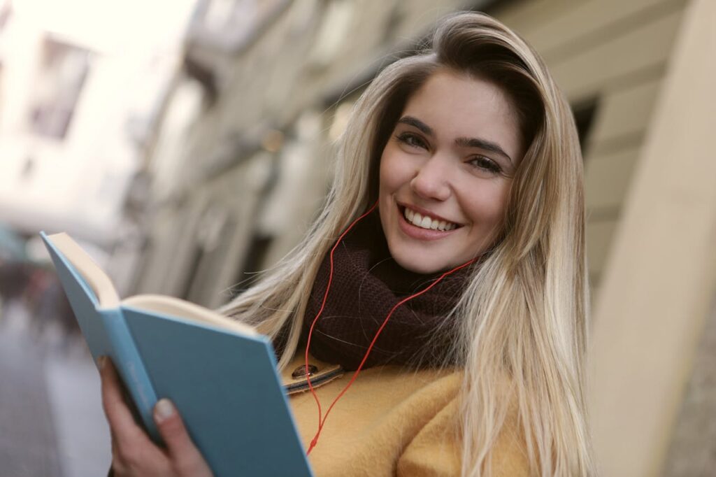 Woman in Brown Coat Holding A Blue Book